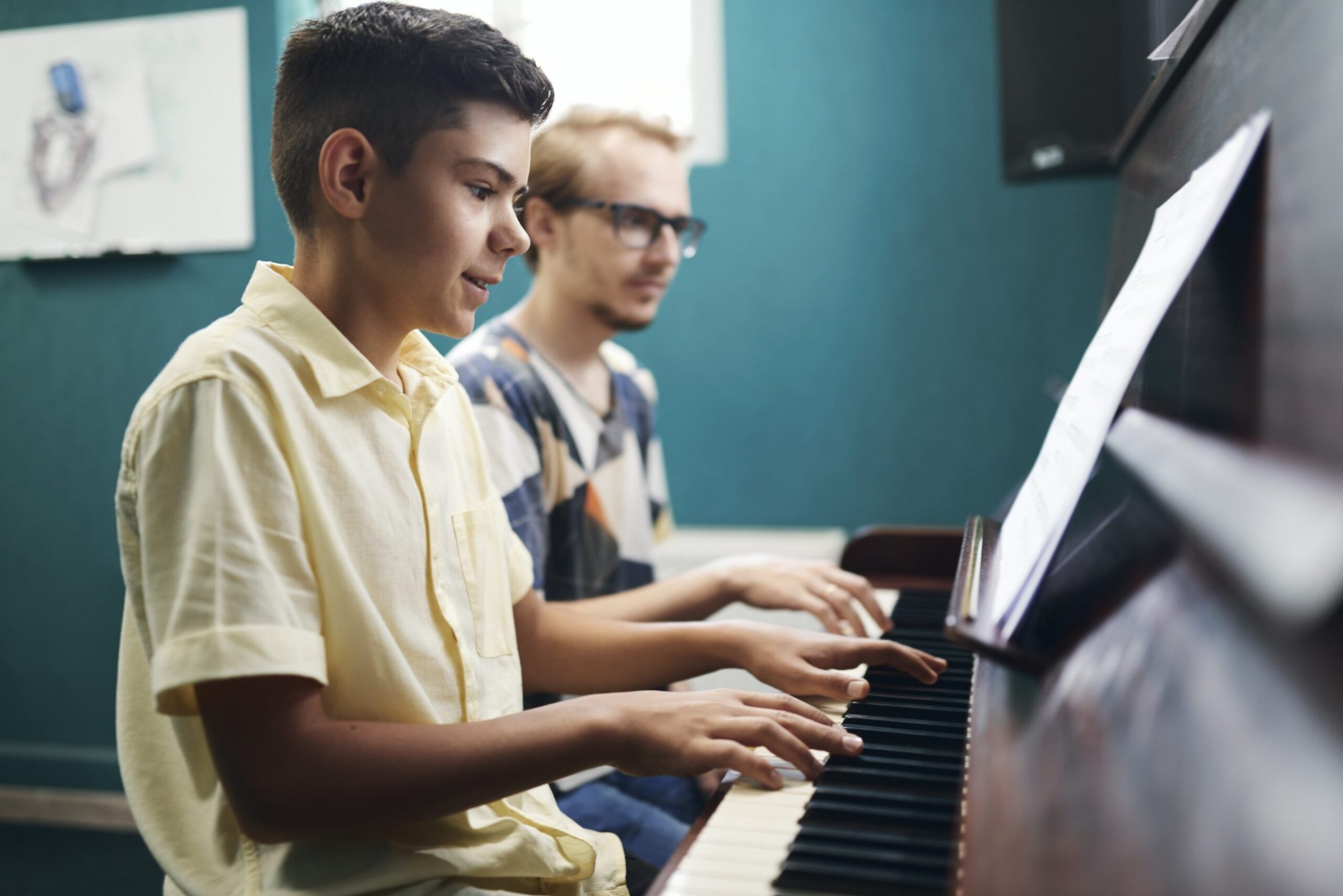 smiling-boy-playing-the-piano-with-his-teacher-2021-09-24-04-29-00-utc.jpg